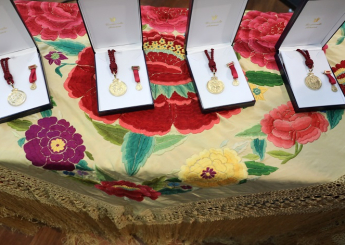 cajas con medallas doradas con cordón granate, sobre una mesa con mantón floreada